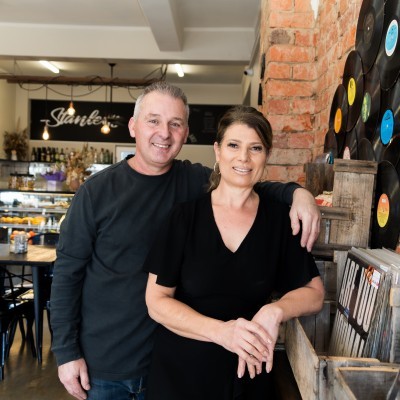 Restaurant proprietors standing next to a vintage record collection