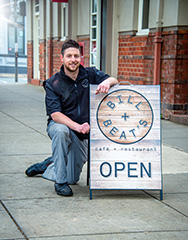 Man knealing in front of Bill and Beats restaurant sign