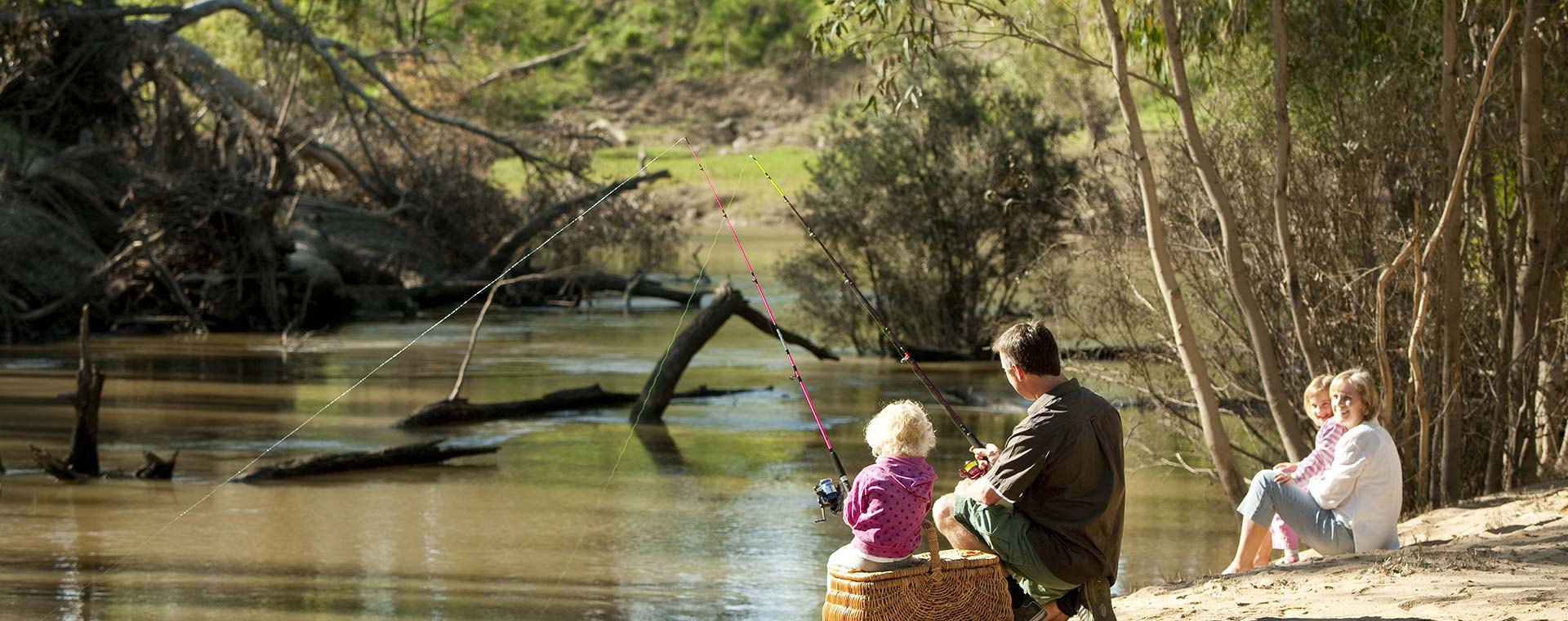 Family enjoying a fishing picnic by the river.